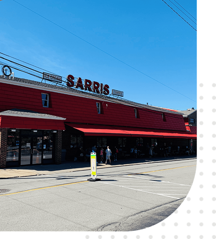 A red building with a green roof and people walking on the sidewalk.