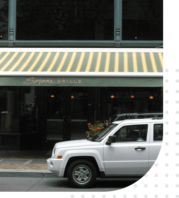 A white jeep parked in front of a restaurant.