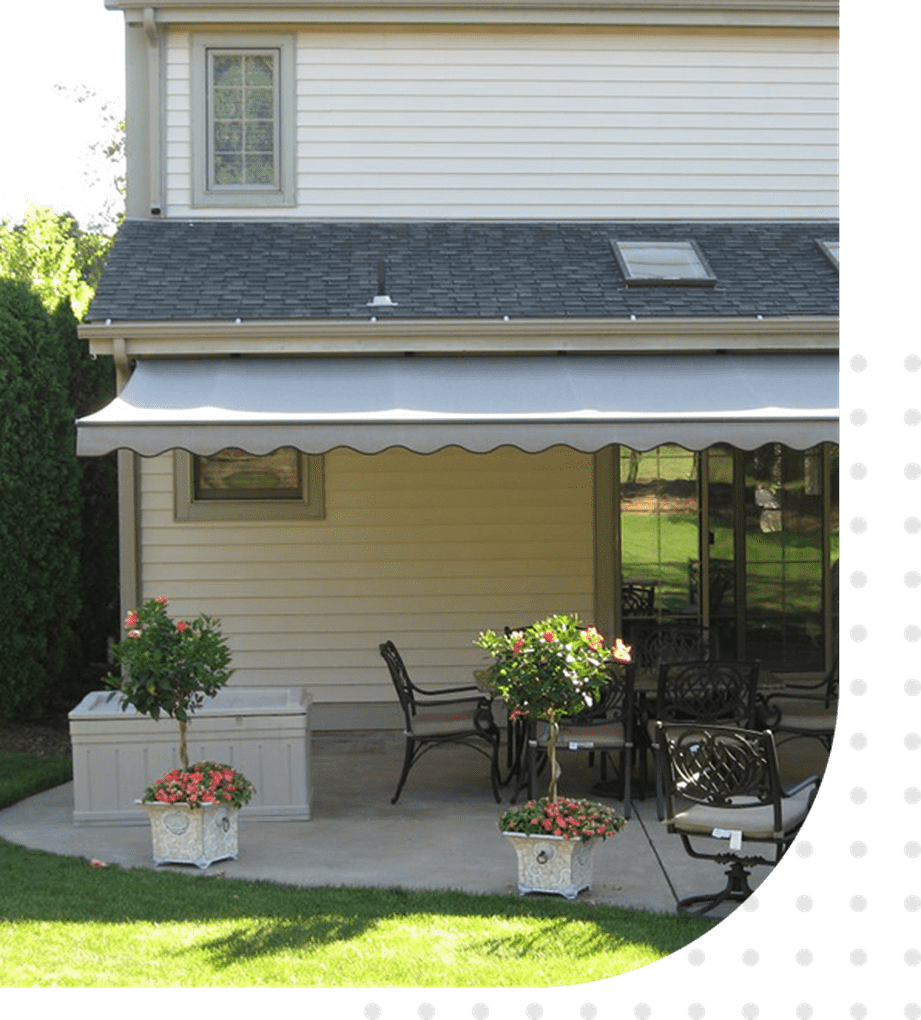 A patio with a table and chairs, potted plants and a house.