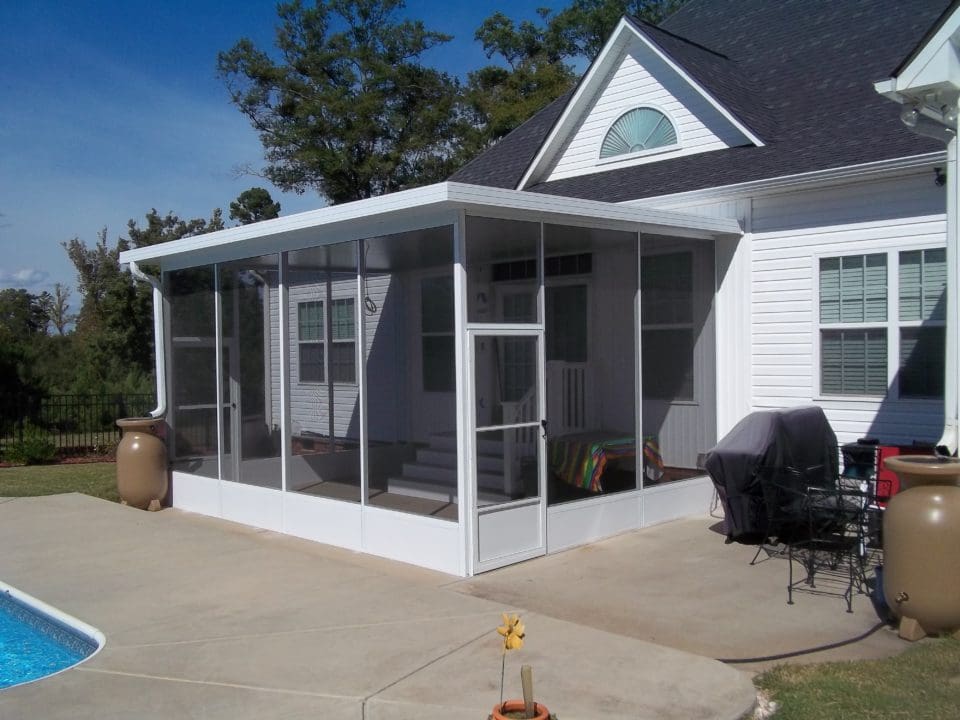 A patio enclosure with a grill and chairs.